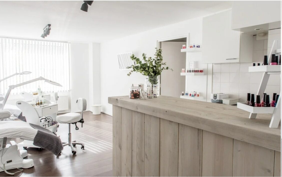 Praktijkruimte met houten balie en nagellakwand